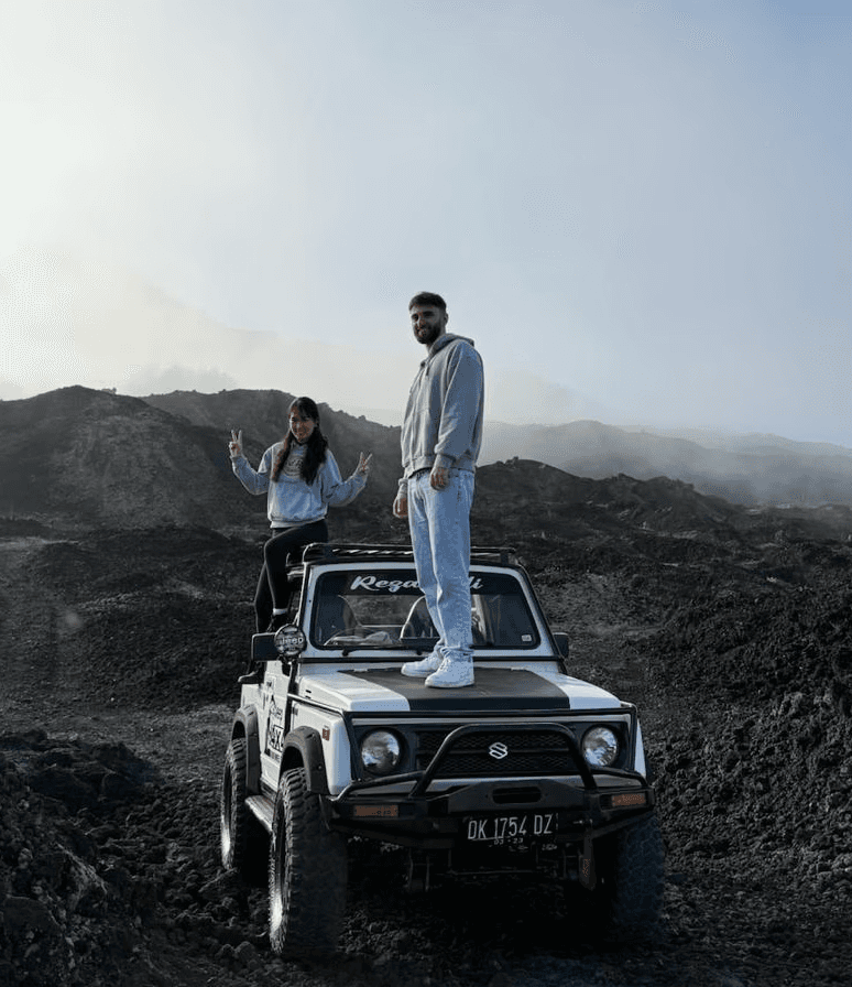 Close-up portrait of a person wearing a gray insulated hooded jacket with the hood up, showing their face framed by the hood against a light background.