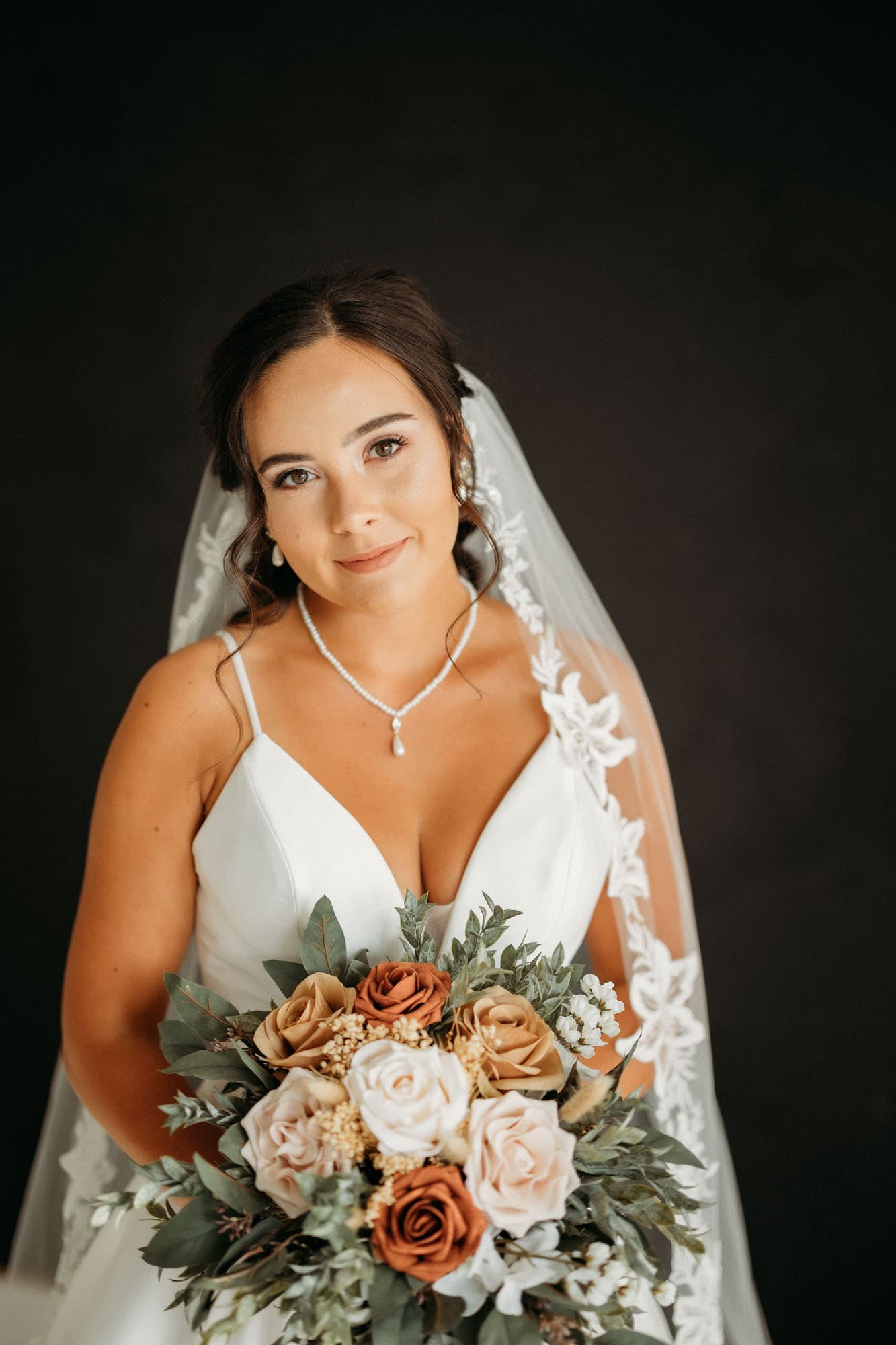 A bride stands with her bouquet in soft natural light, capturing an elegant moment during her bridal session at Revelator Studio in Shreveport.