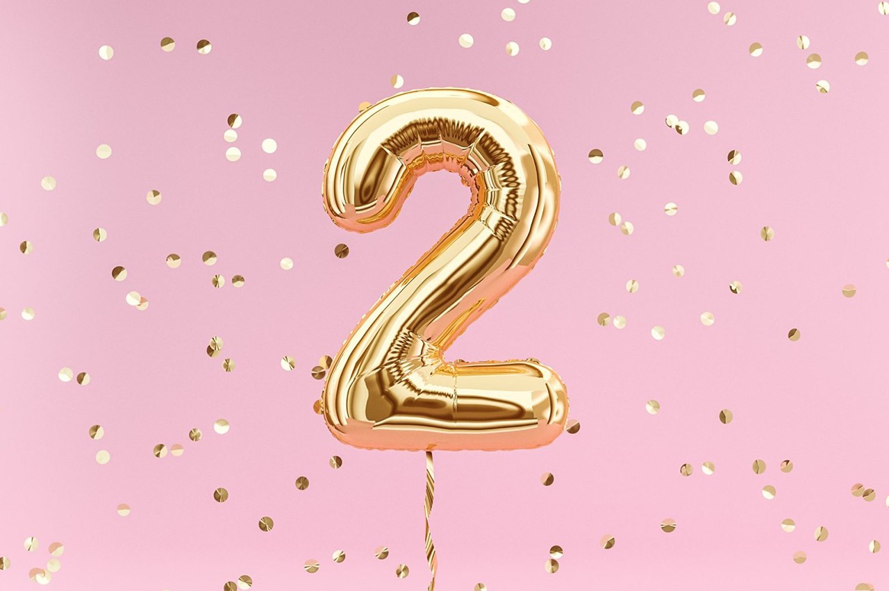 Party balloon in the shape of the number 2 with confetti falling around