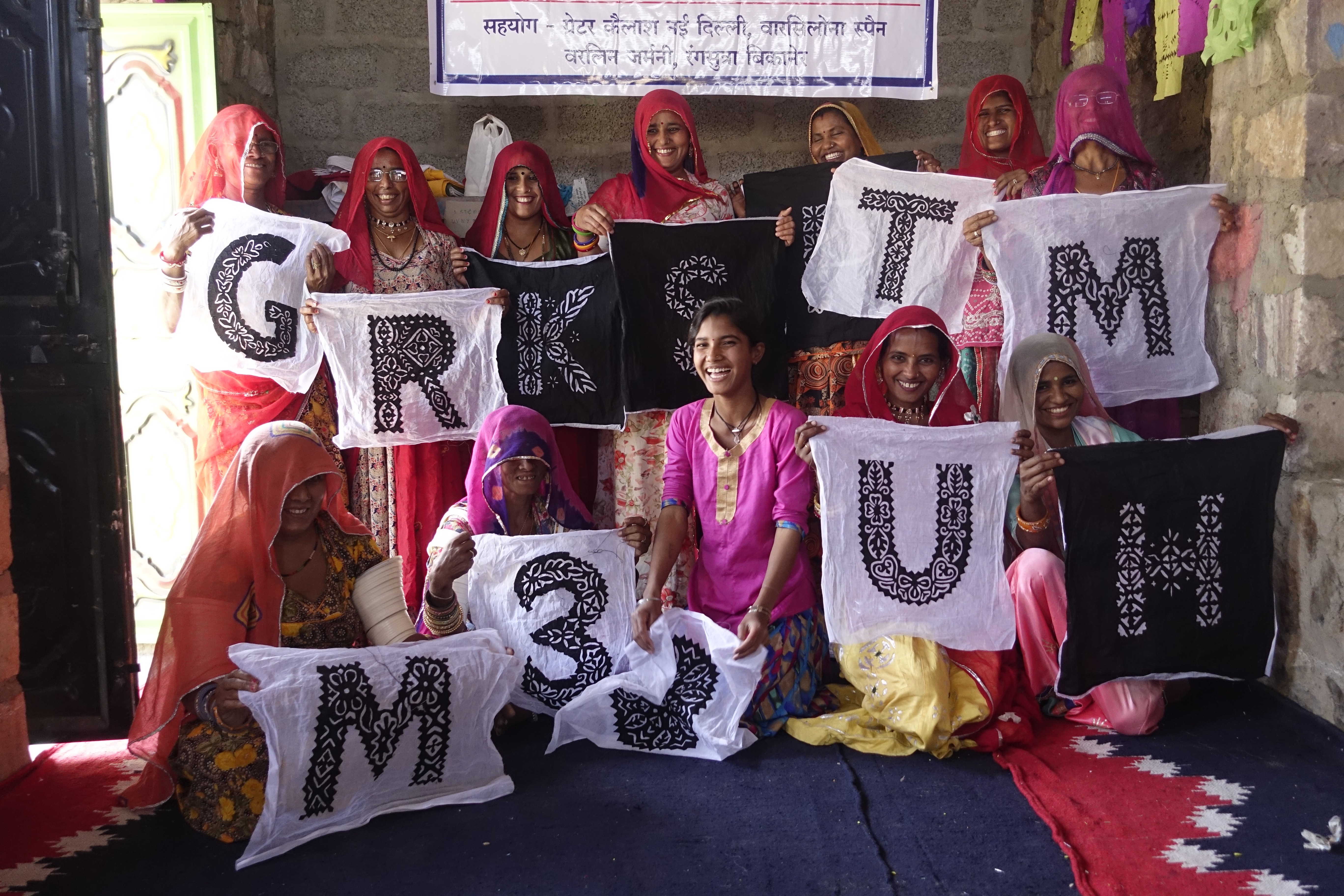 a group of people holding up Indian handcrafted lettering