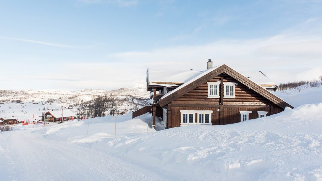 Double log cabin near Vierli Skisenter with snowy mountains in the background