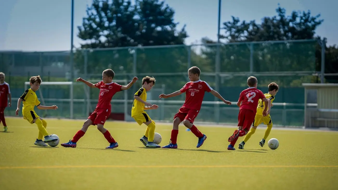 Kinder spielen Funino, den innovativen Fußballspielmodus, der speziell entwickelt wurde, um Spielvermögen, Kreativität und technische Fähigkeiten im Fußball für Kinder zu fördern. Junge Spieler in bunten Trikots treten auf einem kleinen Fußballfeld in einem 2-gegen-2-, 3-gegen-3- oder 4-gegen-4-Spiel gegeneinander an, das die grundlegenden Prinzipien von Funino demonstriert.