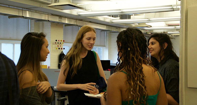 A photo of a group of people sitting in an office room and talking.