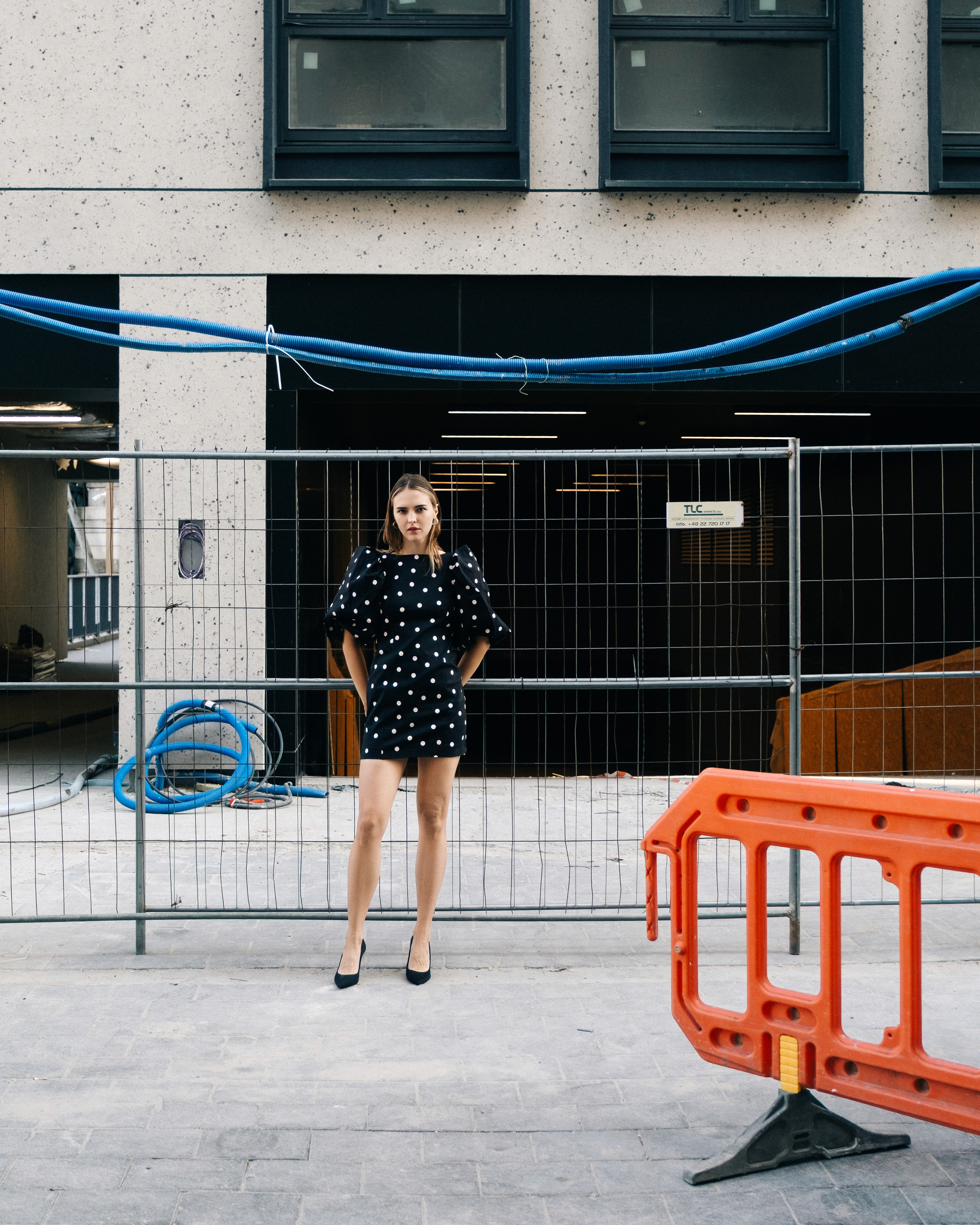 Ania – She Owns the City - standing behind fencing at a construction site.