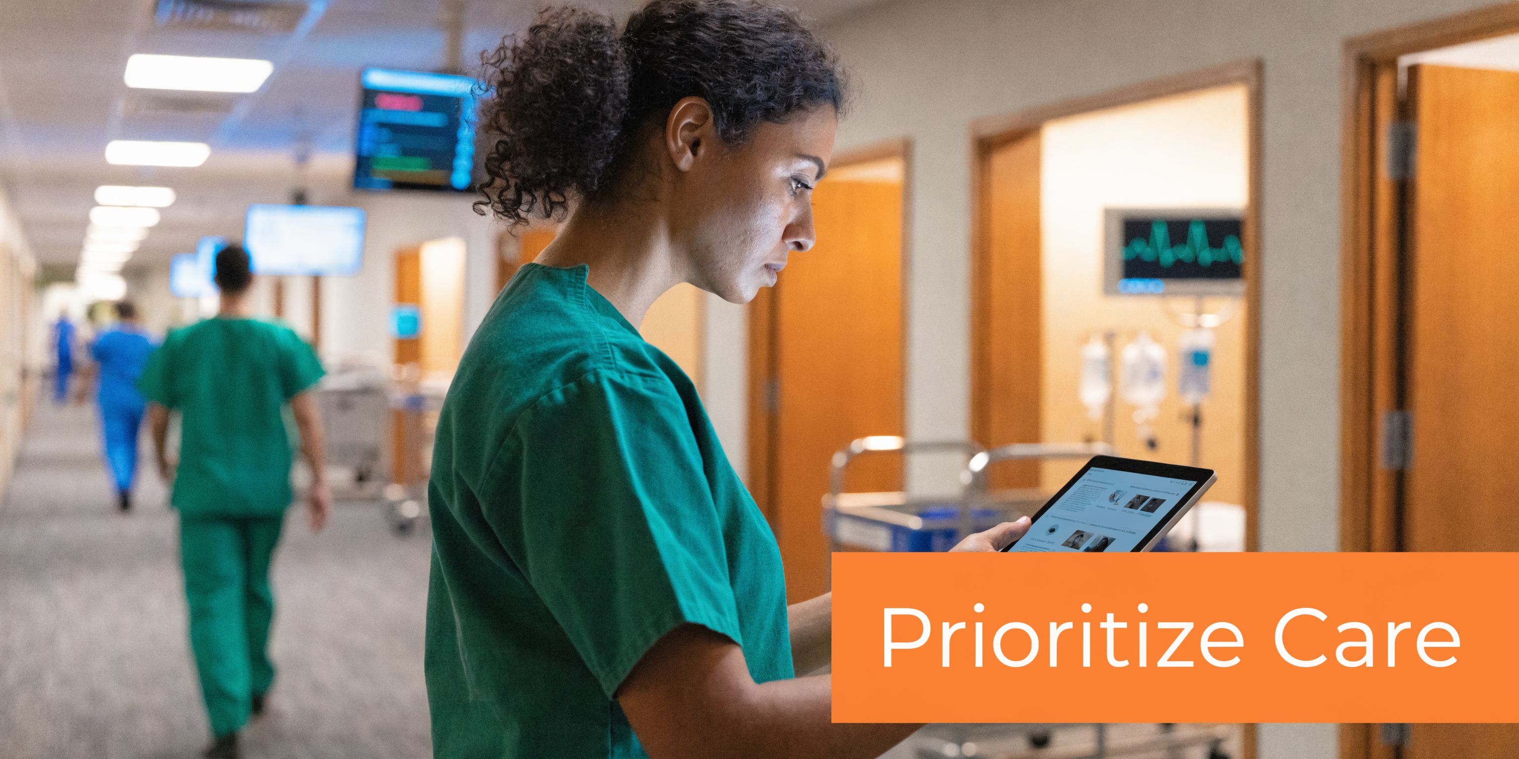 A female healthcare professional standing in a hospital corridor looking at a digital tablet.