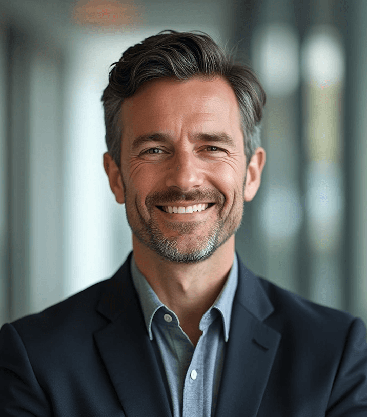 A woman wearing a red blazer is seated on a chair, looking confidently at the camera.
