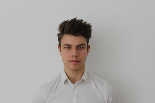 Samuel Mitterrutzner, Co-Founder and CTO of CoachingArea, standing in front of a plain white background, wearing a white dress shirt and looking directly into the camera with a serious expression. His hair is styled upwards, giving a professional and confident appearance. He is the author of this article.