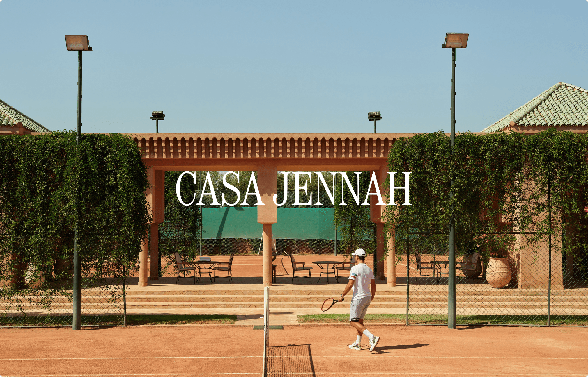 Joueur de tennis sur court en terre battue entouré de végétation et d'architecture marocaine. Texte "Casa Jennah"