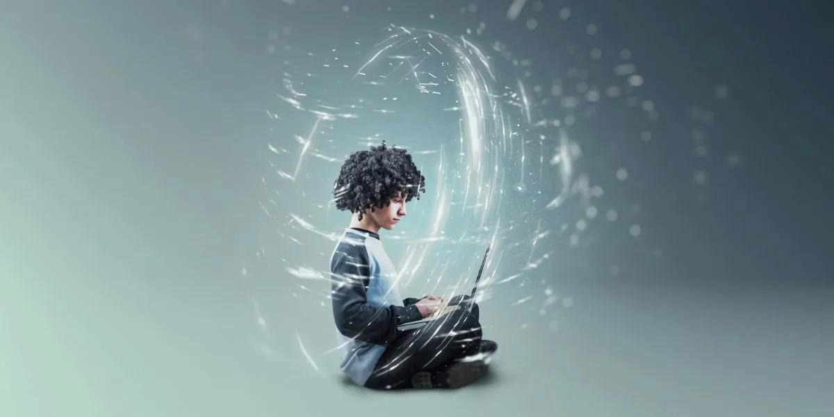 A man stands while two people sit at a table in an office setting, smiling and engaged in conversation. The mood is friendly and collaborative.