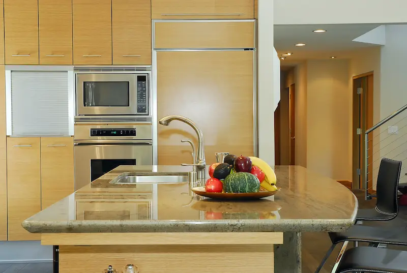 Modern kitchen island facing panel-ready fridge cabinetry and stainless steel appliances. Irvine Transitional Modern Project. Photo by Chris Darnall.