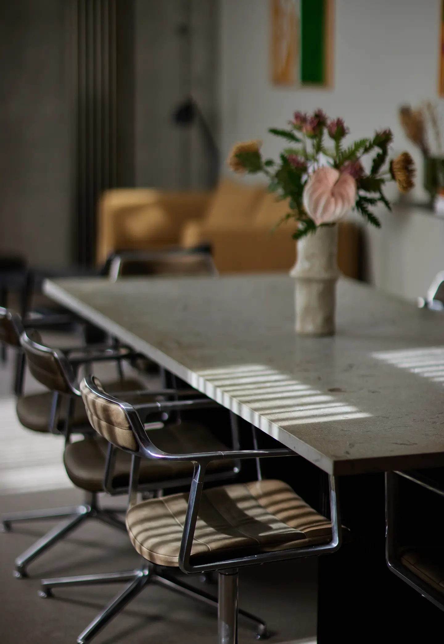 Meeting table with leather chairs and a vase of flowers in soft focus