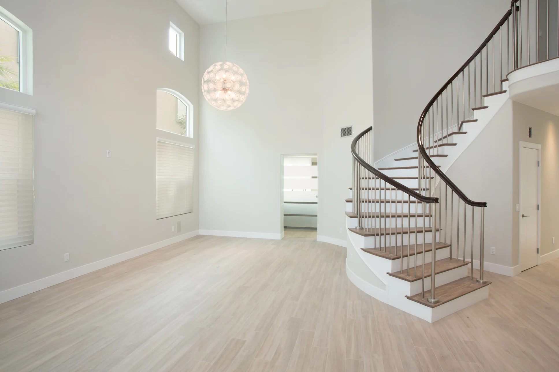Wide view of the main entry featuring the spiral staircase with solid oak treads and brushed stainless steel pickets, a centerpiece in this Harbor Cove home.