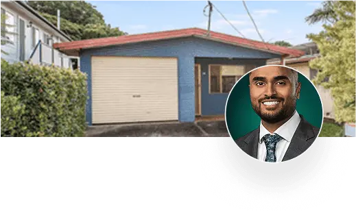Man in suit next to blue house with garage