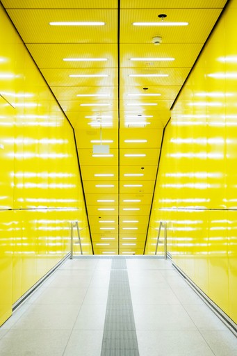 Modern yellow hallway with bright overhead lights
