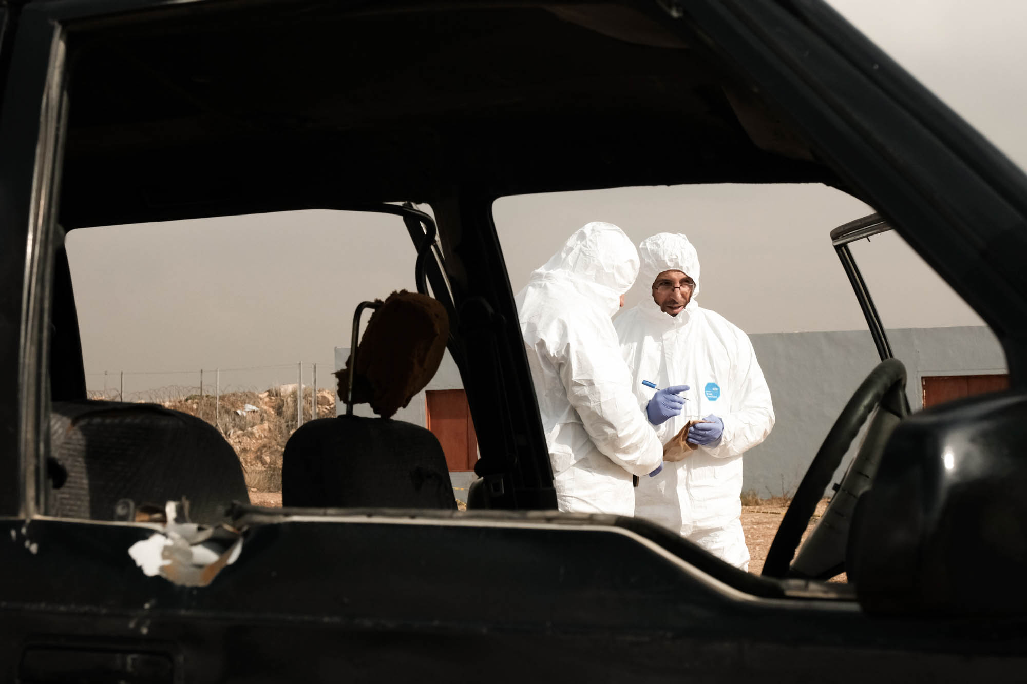 Two policemen seen examining a burnt-out car during a post blast training exercise