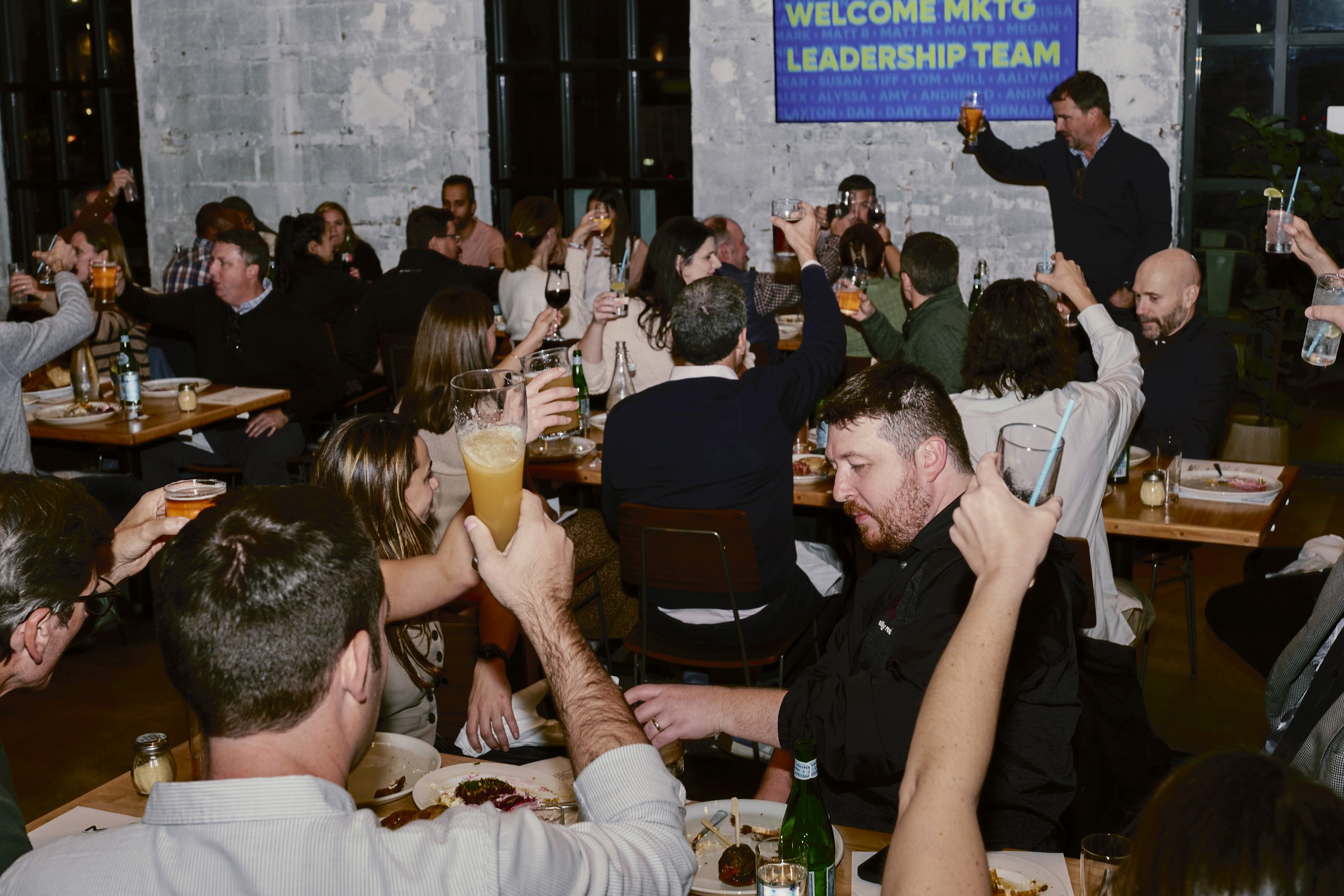 Black and white image of people working at a table with laptops, showing hands gesturing during discussion of digital content displayed on screens, with fabrica® logo in the corner.