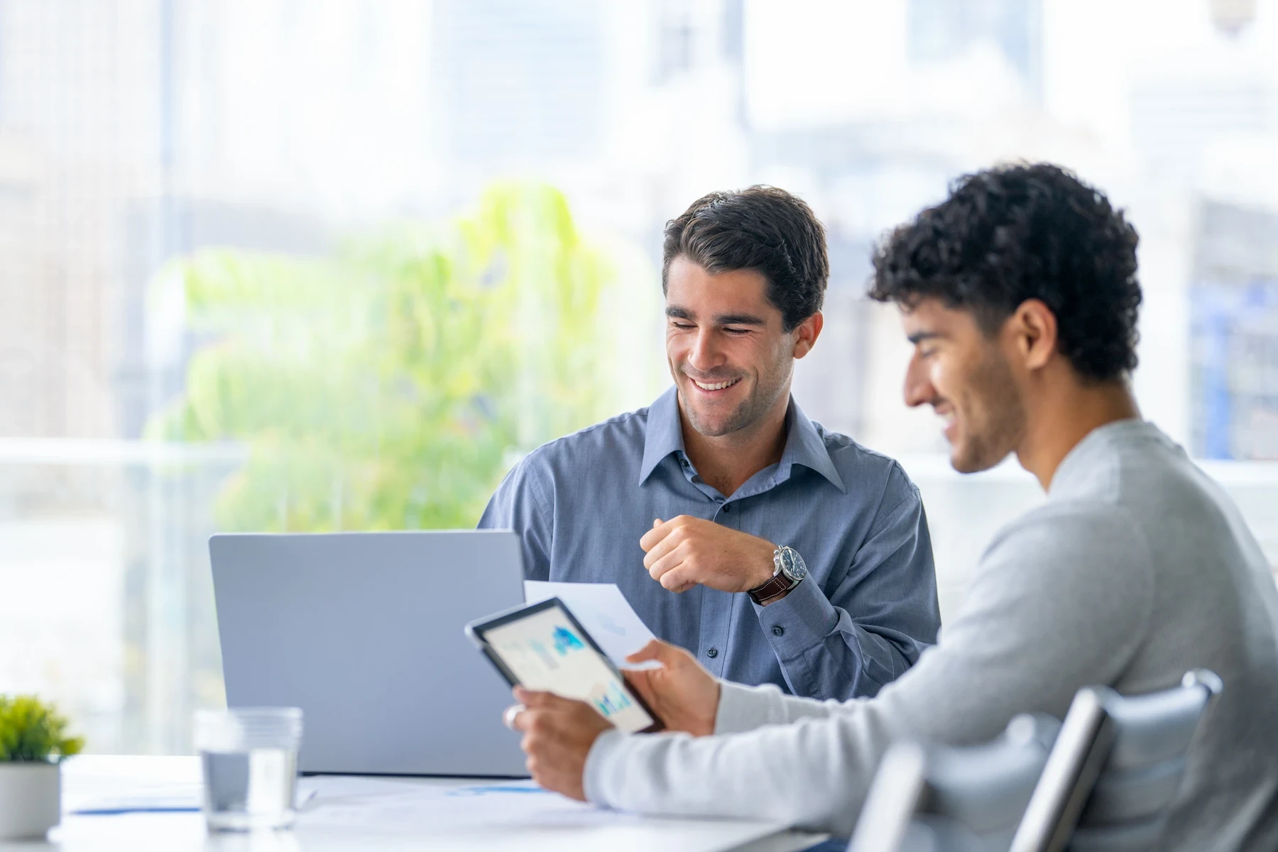Two professional smiling and checking their devices and graphs are displayed