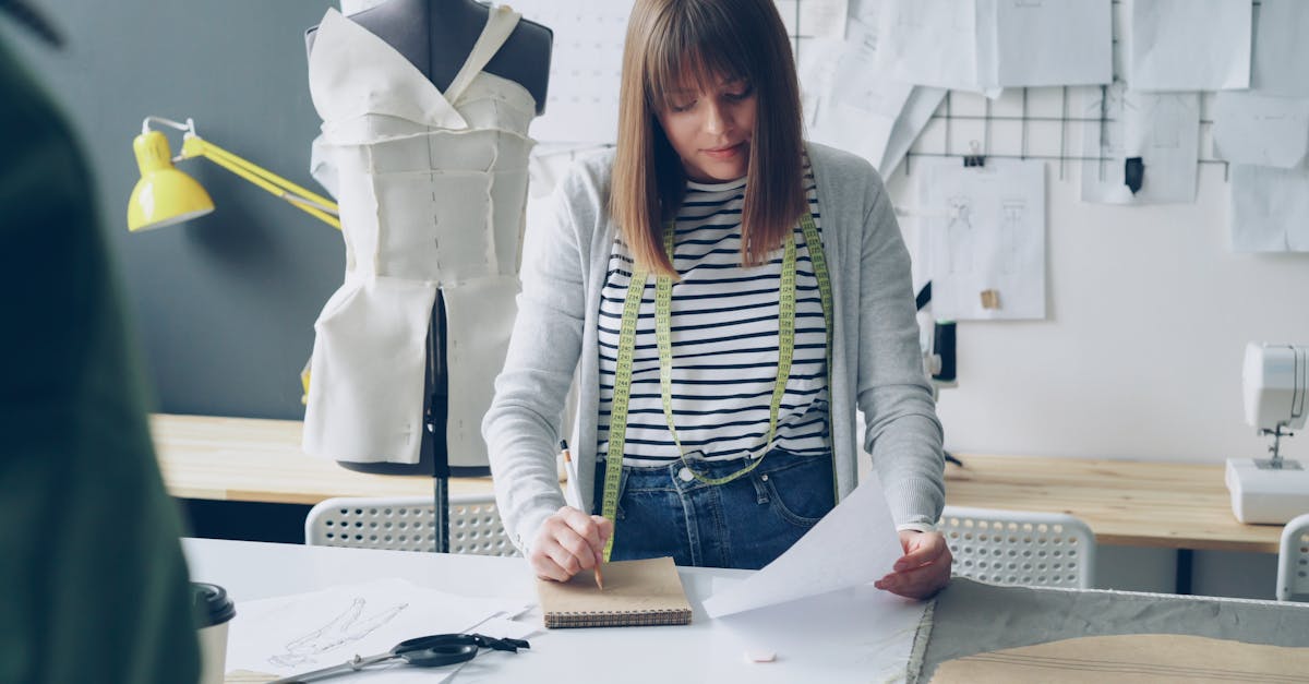 Fashion designer sketching ideas at a workstation with a dress form in the background.