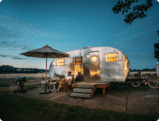 A couple sitting in front of the caravan. They seem to be enjoying