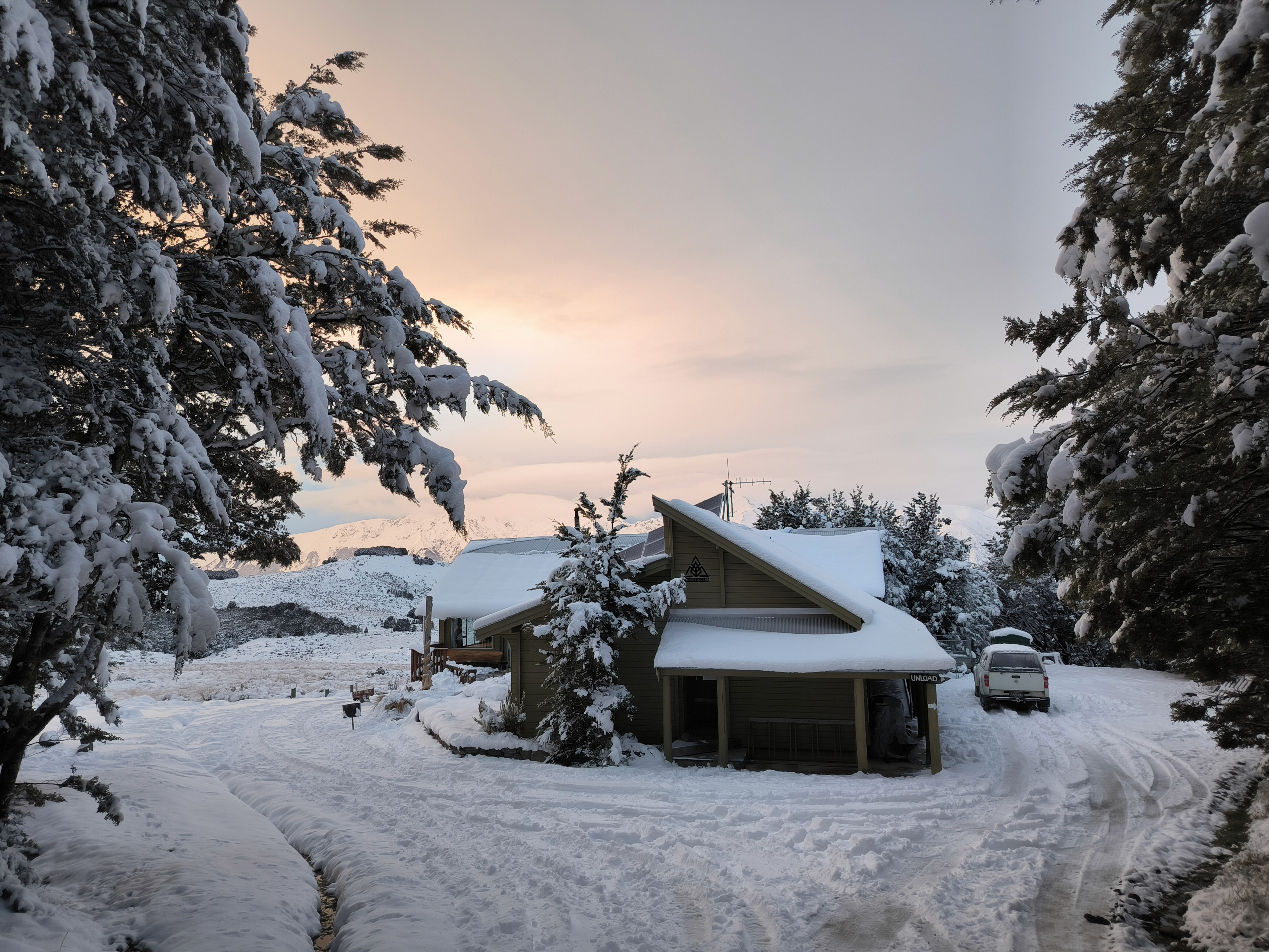 A lodge on New Zealand's South Island with snow on the roof, and roads and trees covered in snow