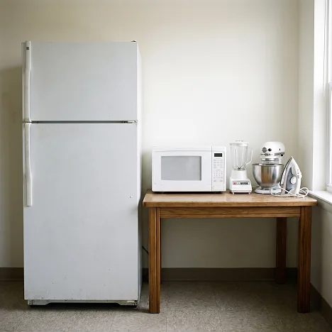 Fotografía de electrodomésticos en una cocina, mostrando una refrigeradora, una lavadora y un horno microondas para recojo.