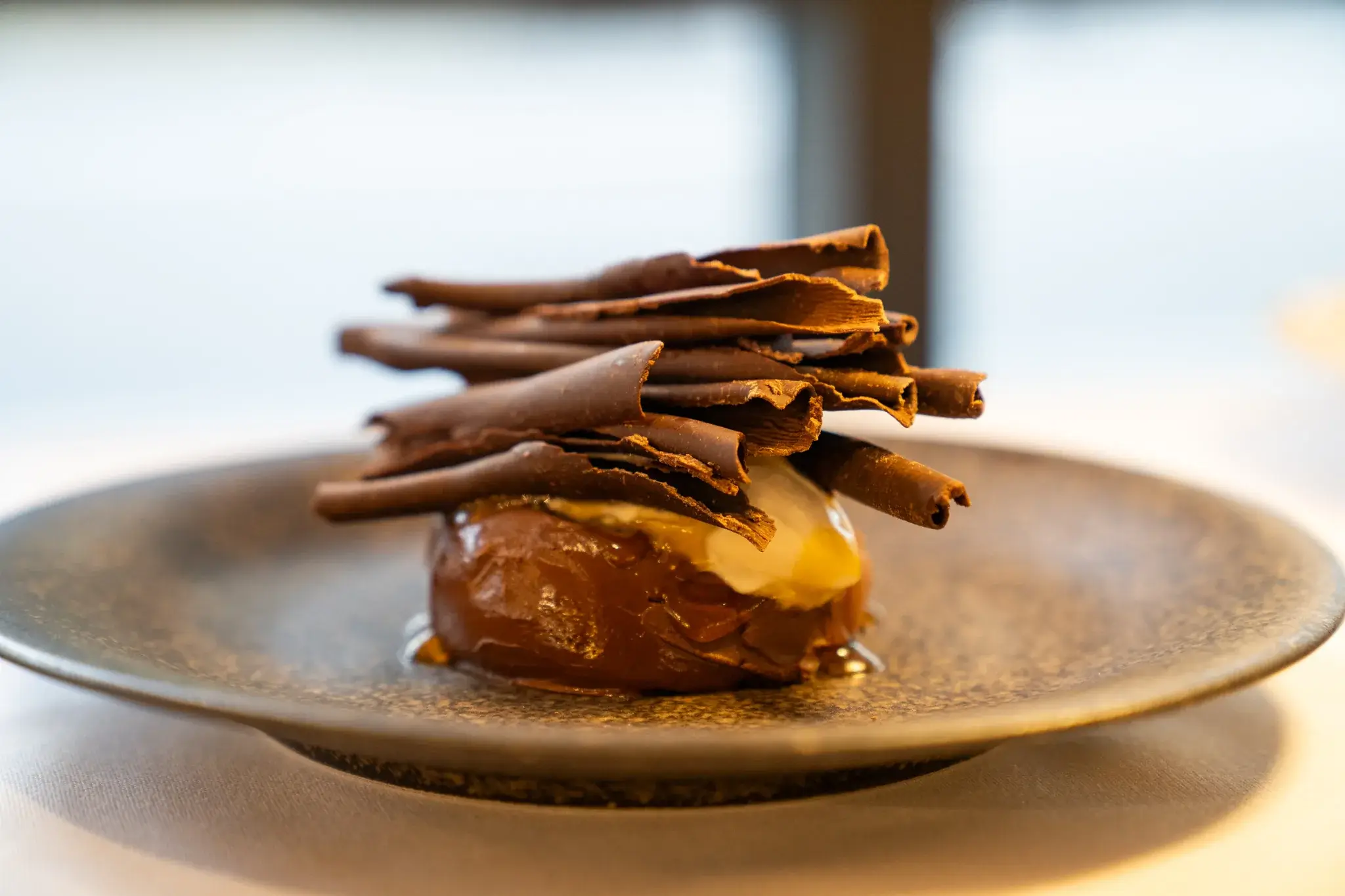 Chocolate dessert with dark chocolate shards and cream on a stoneware plate
