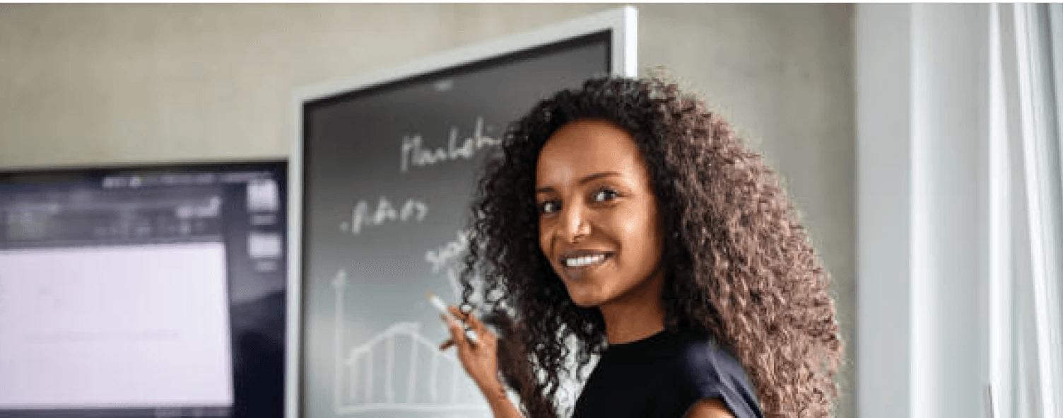 A lady teaching with a black board behind her