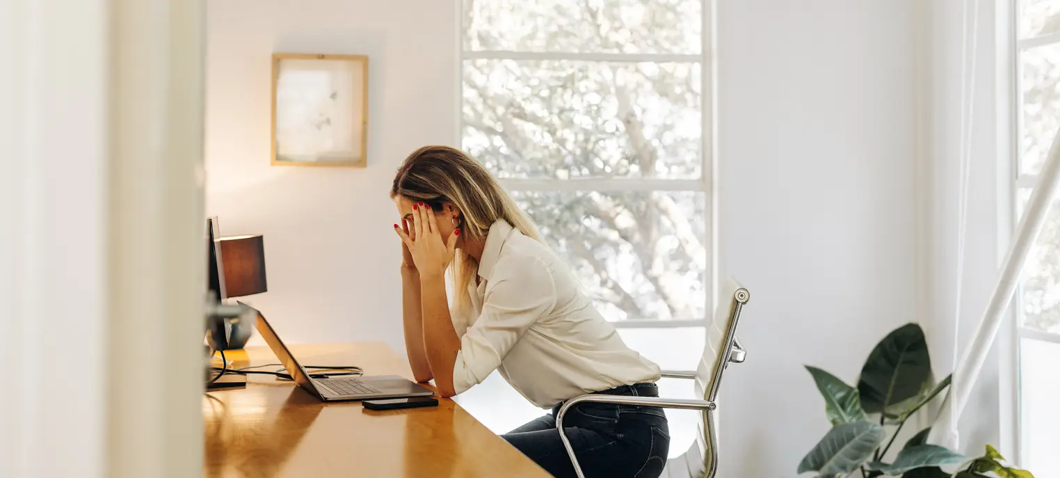 Professional woman experiencing workplace stress and burnout at her home office desk
