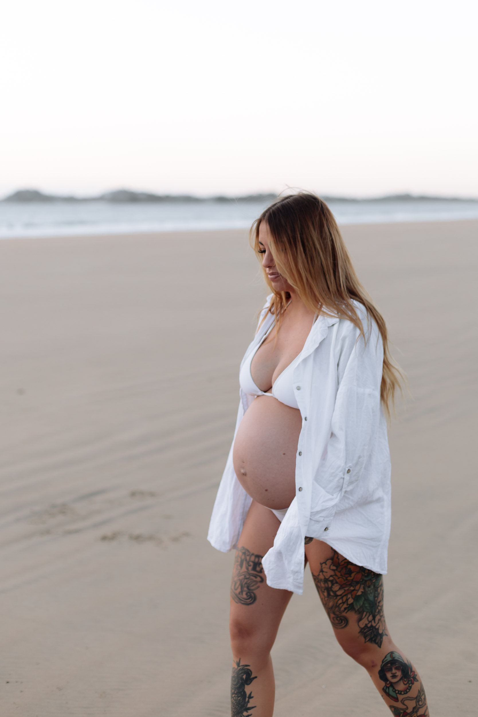 Pregnant woman walking along the shoreline at sunrise in Mackay