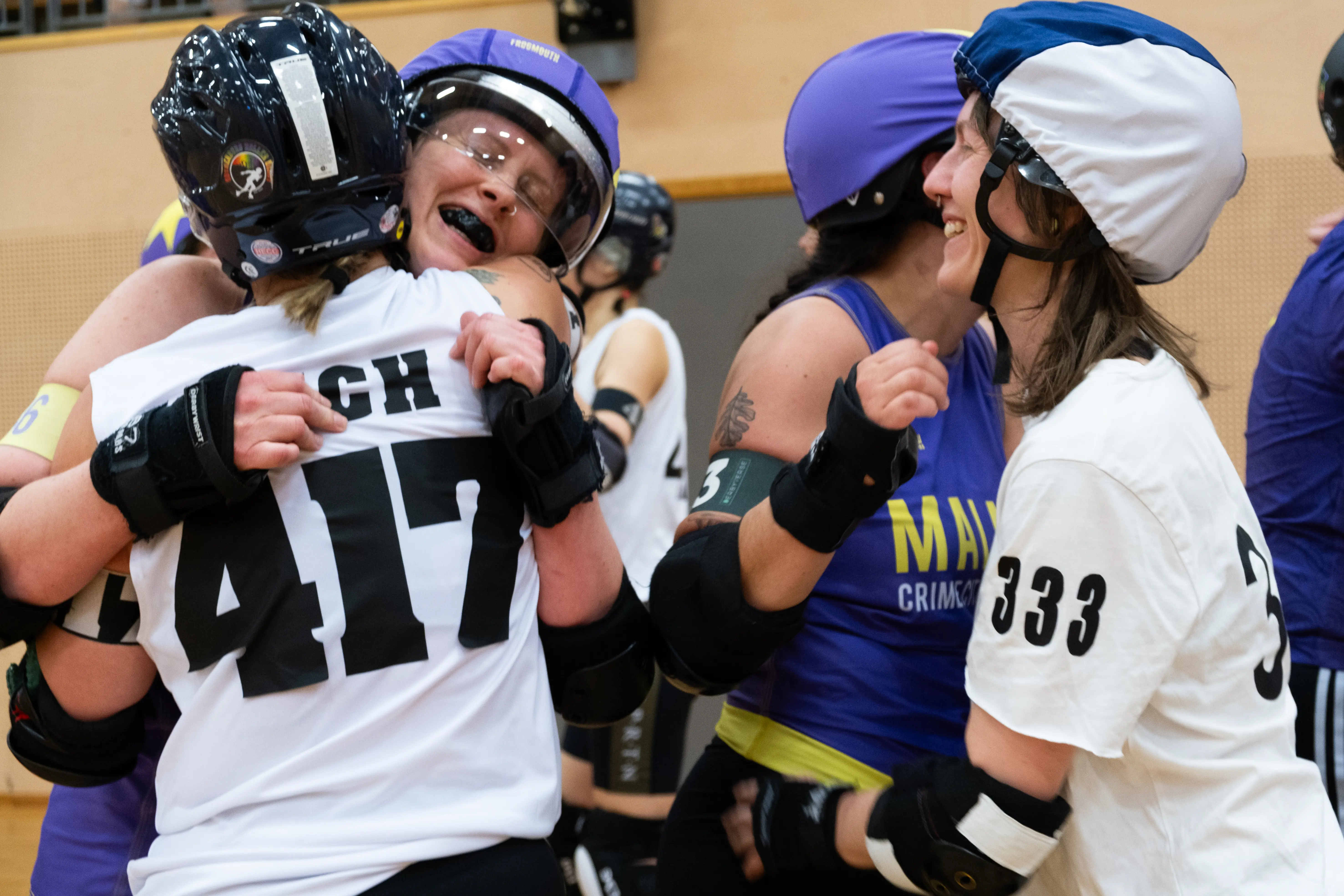 A group of roller derby players hugging after a game.