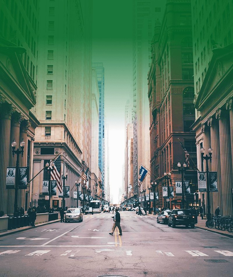 Pedestrian walking through a downtown city street lined with tall buildings