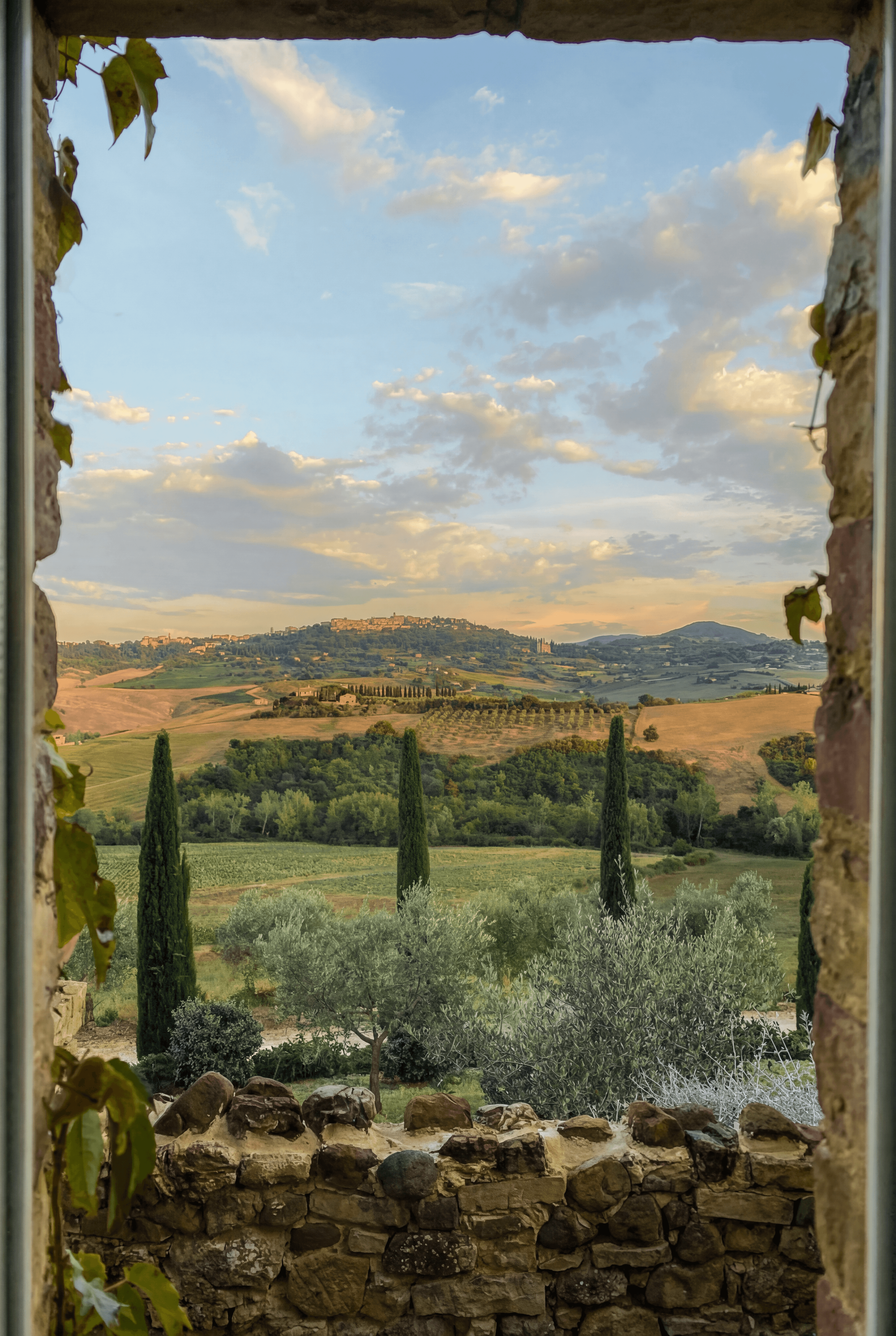 sunset view of the Italian countryside through the window of a historic farmhouse
