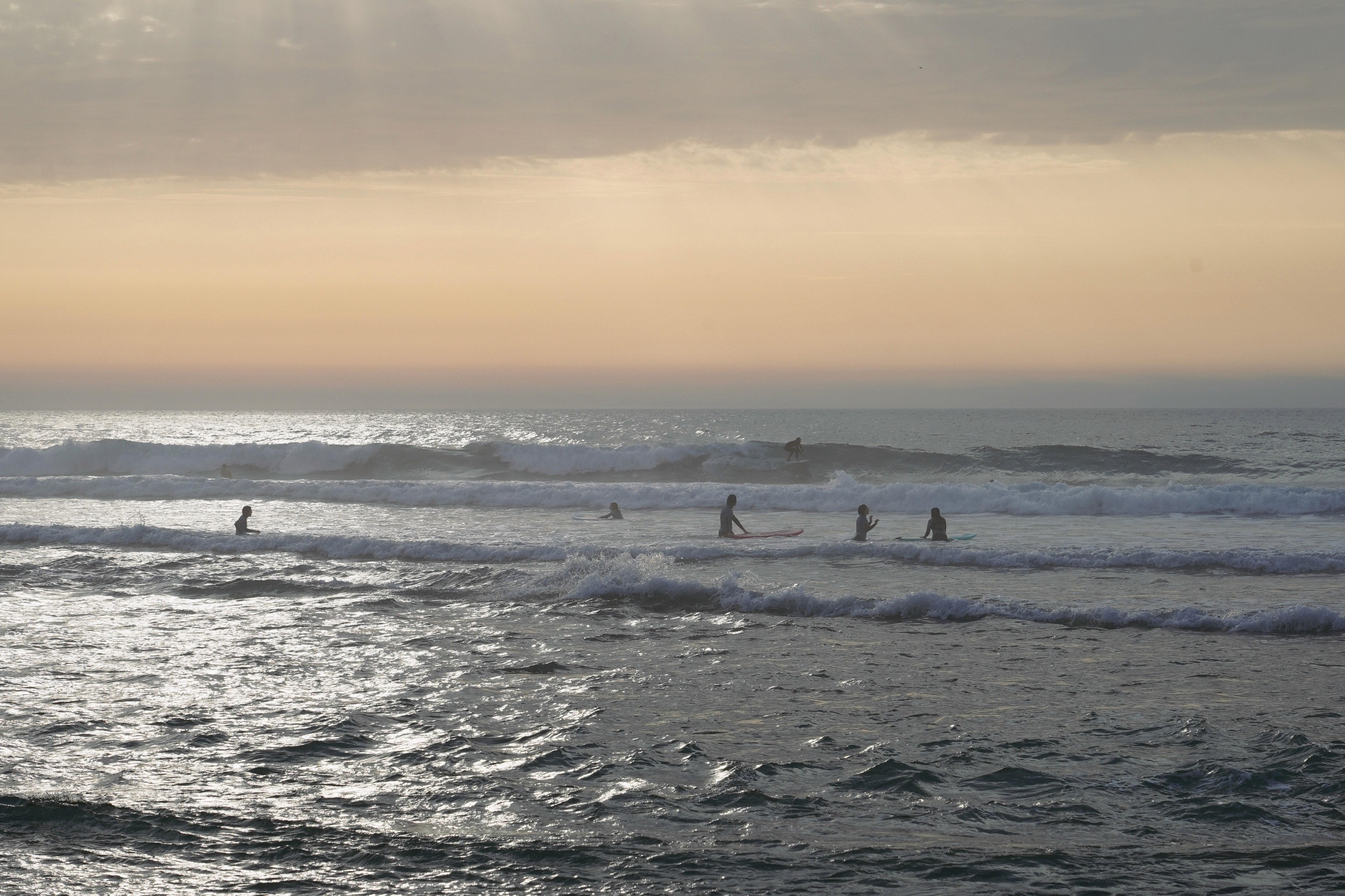 Atardecer en una playa con surfistas