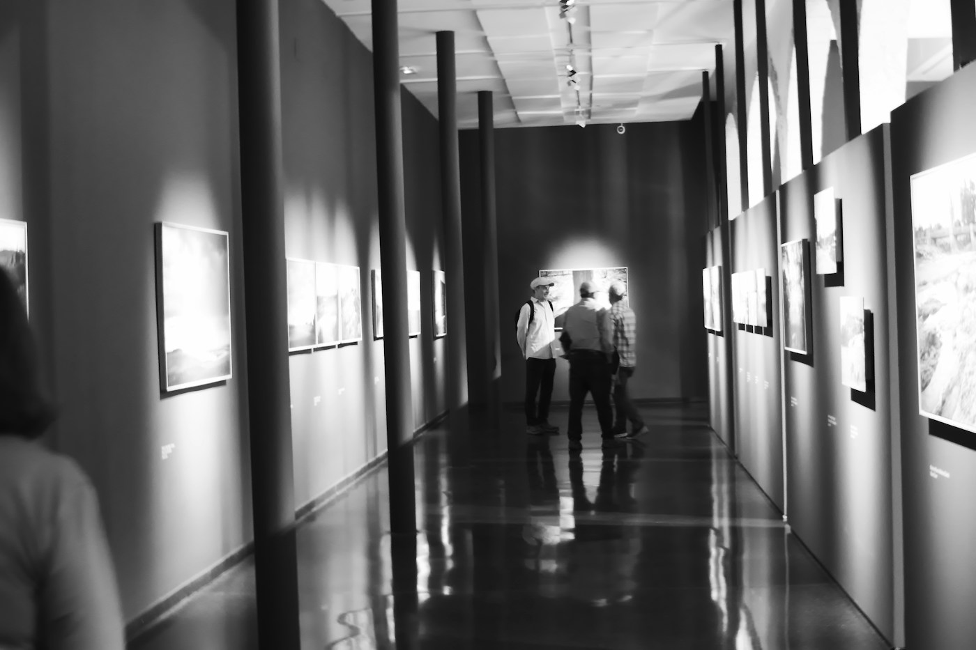Long gallery corridor with framed works and a pool of light