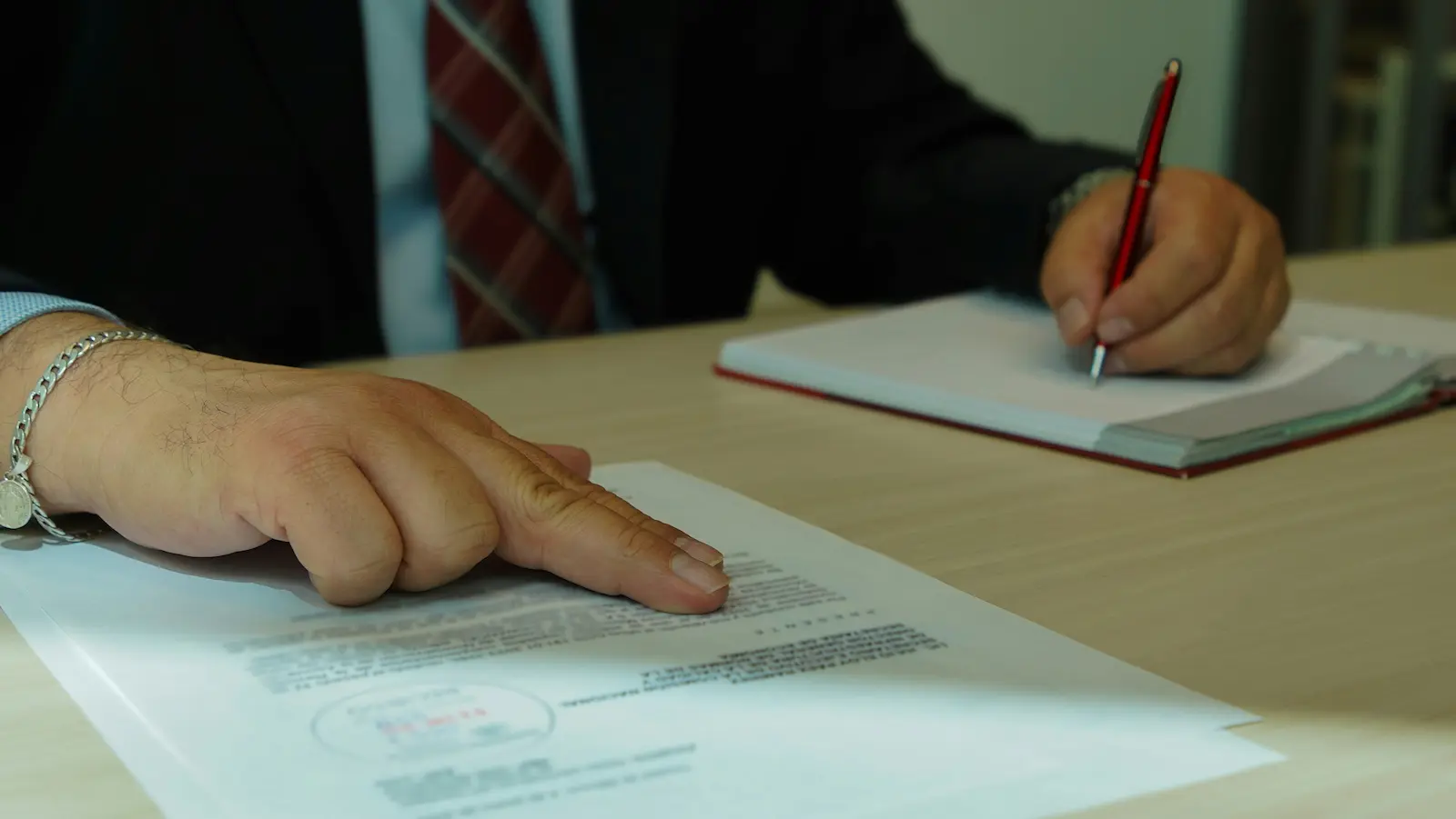Lawyer reviewing a payment agreement and taking notes in a notebook