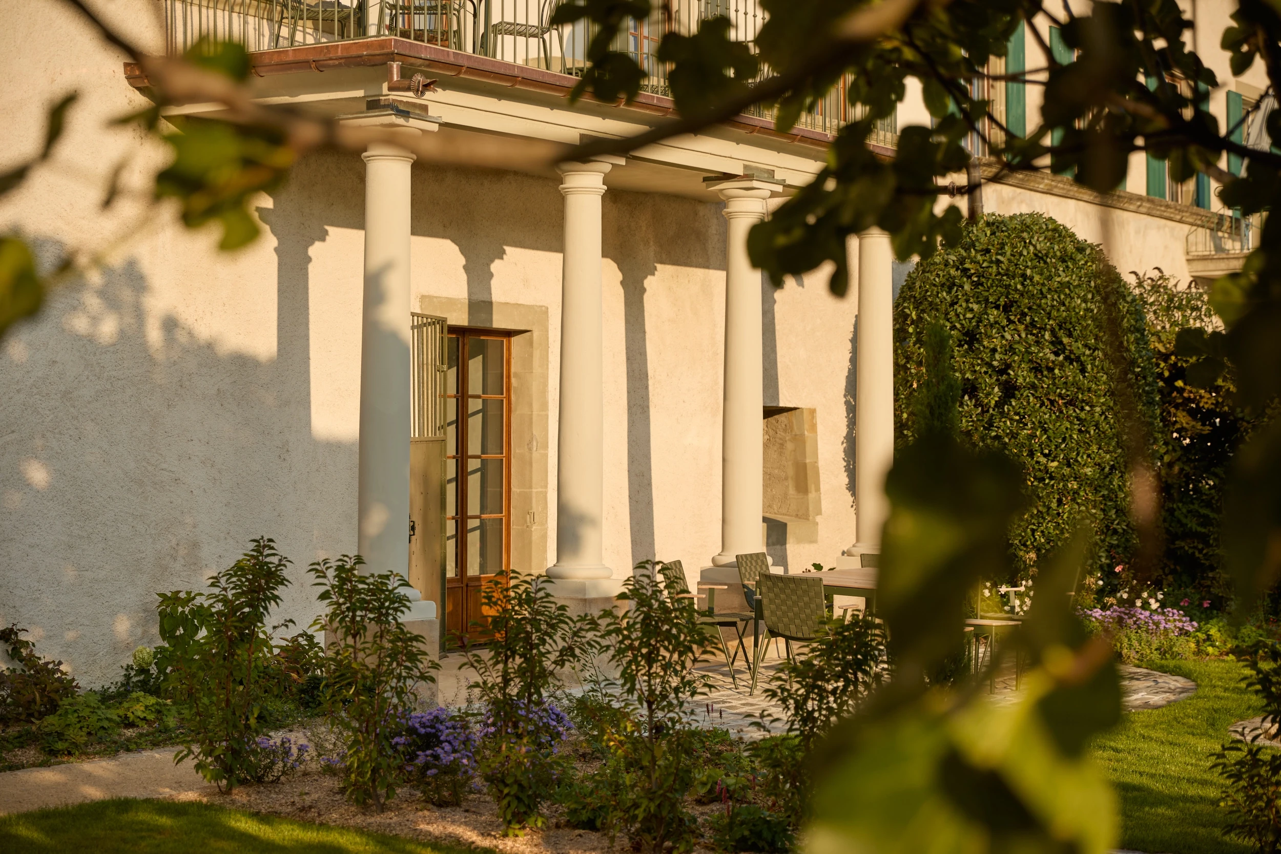 Vue du portique néoclassique du Château de Saint-Prex dans son jardin historique restauré, élément architectural majeur du domaine au bord du lac Léman.
