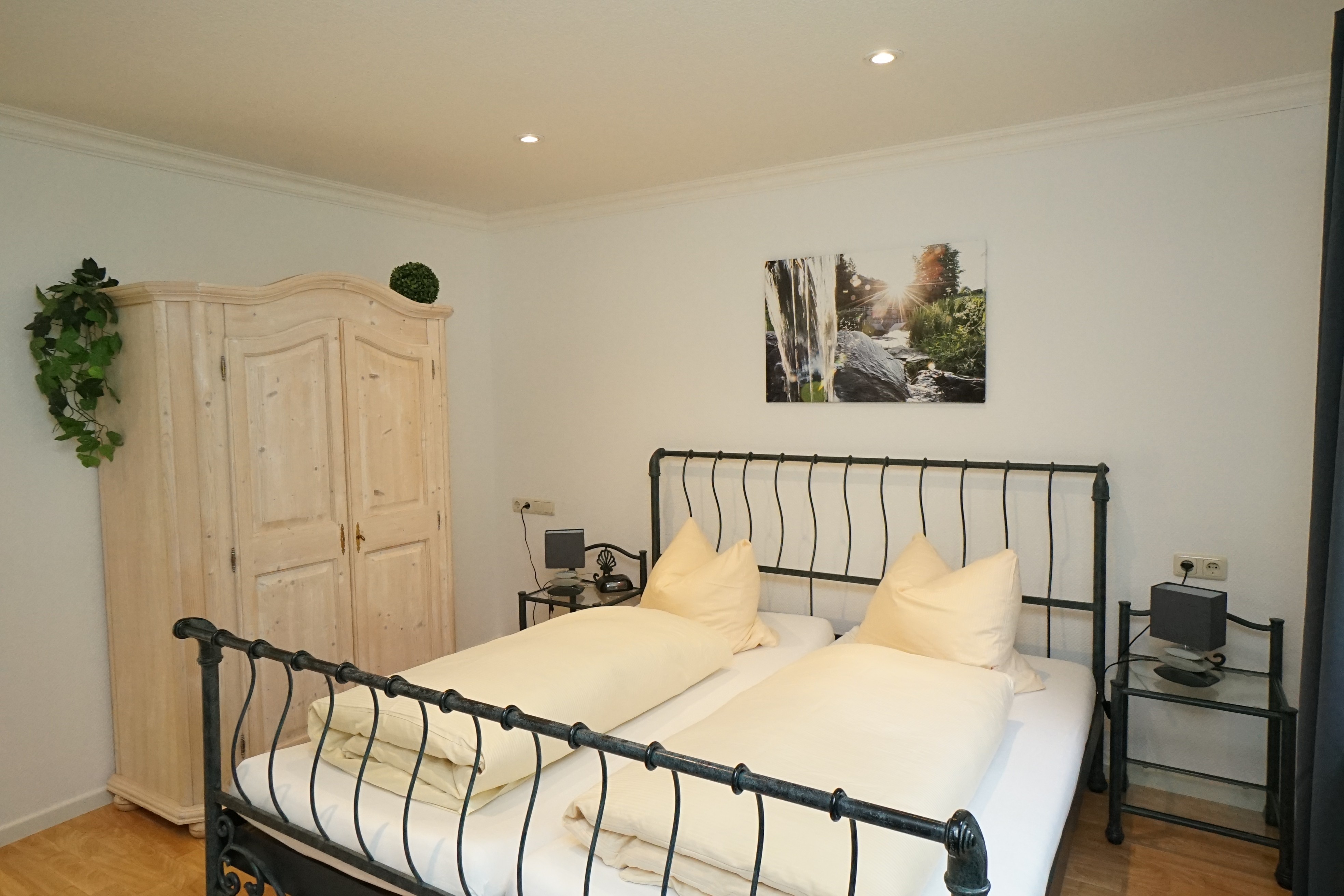 Room with metal bed and white wooden wardrobe