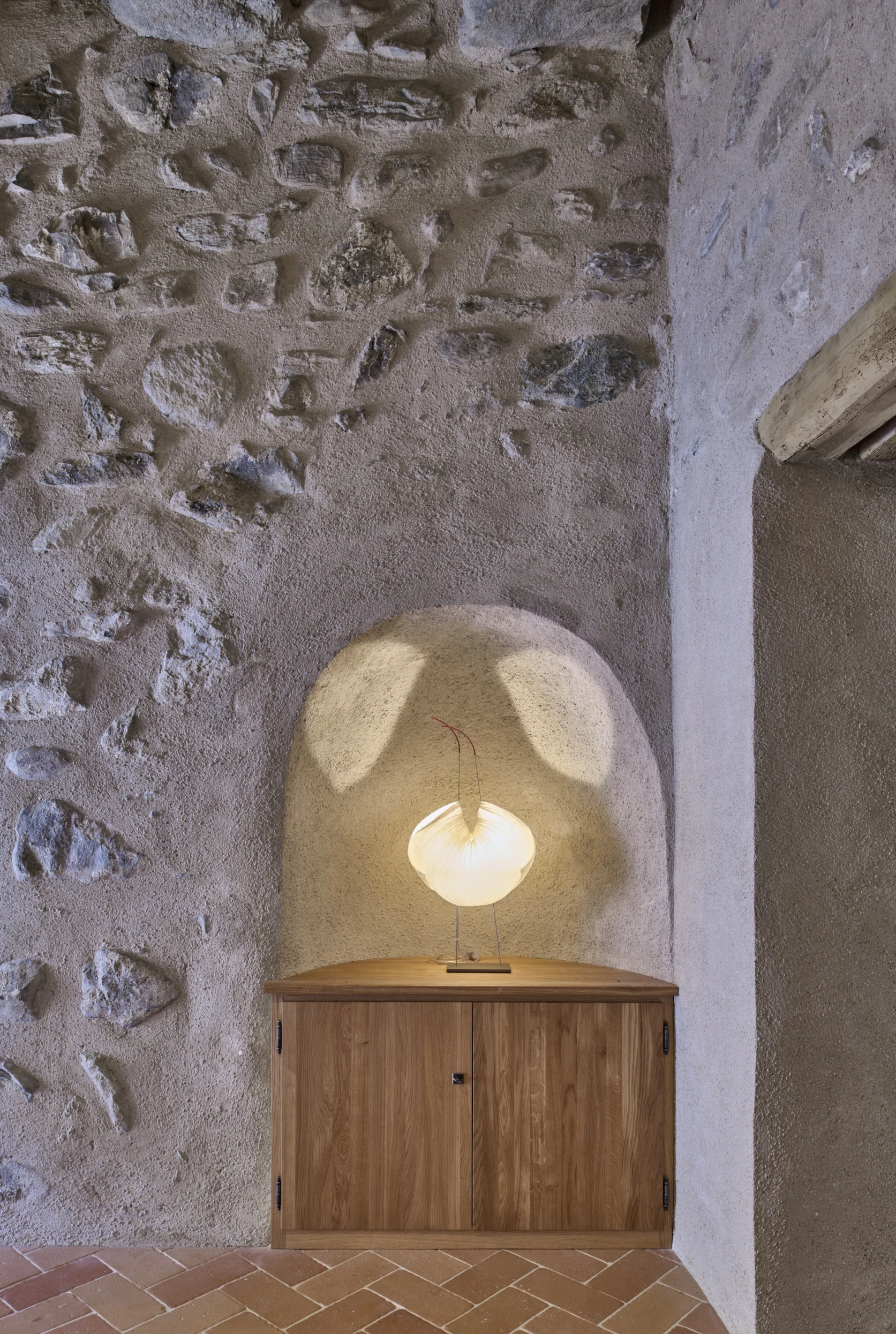 Détail de la réfection des enduits intérieurs et de la maçonnerie dans la tour du Château de Saint-Prex, avec niche éclairée par un luminaire Noguchi et sol en tommettes.