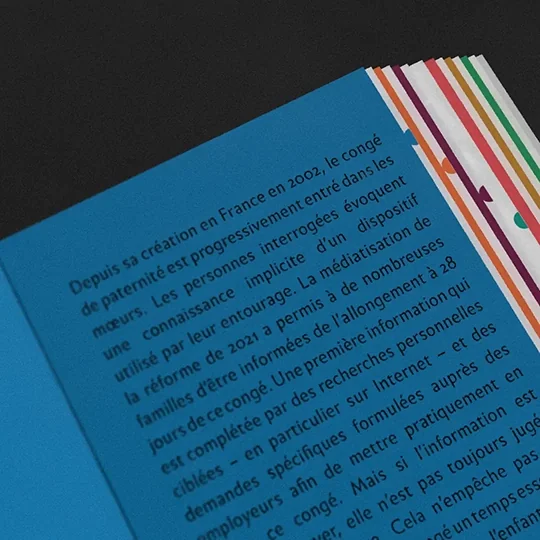 Zoom sur une double page bleue. On aperçoit le chapitrage en points colorés sur la tranche du livre.