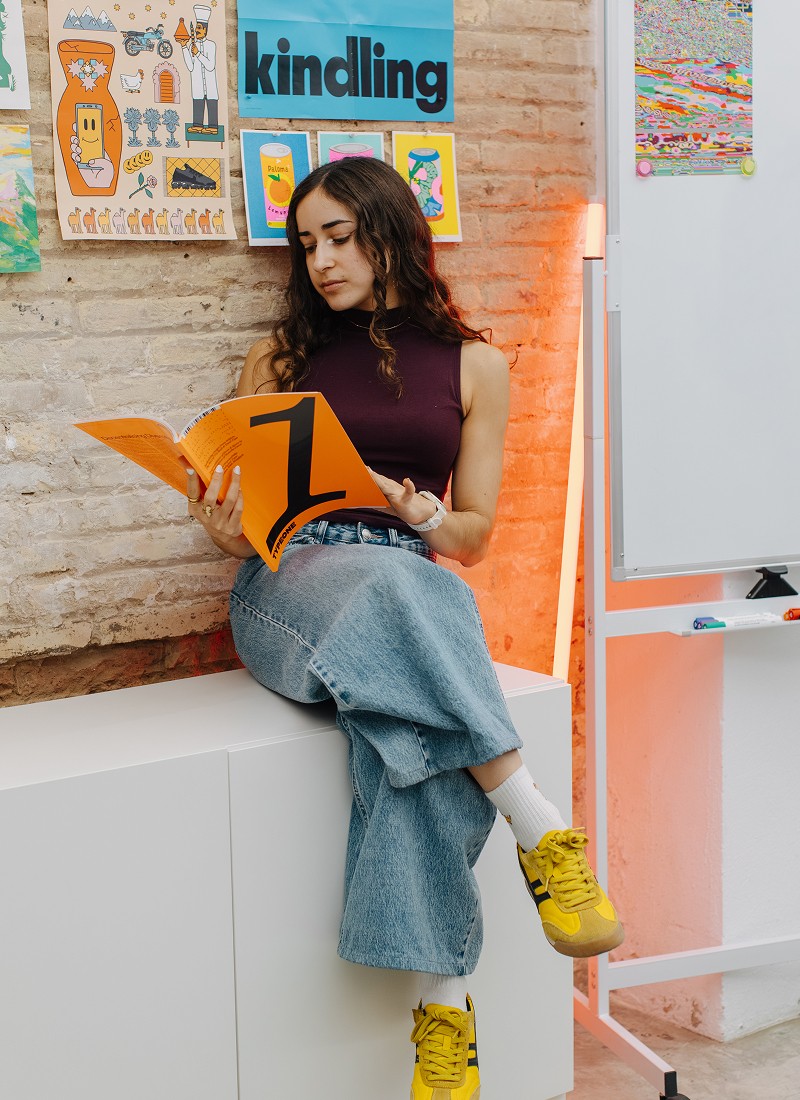 A woman sitting on a cabinet, reading a magazine