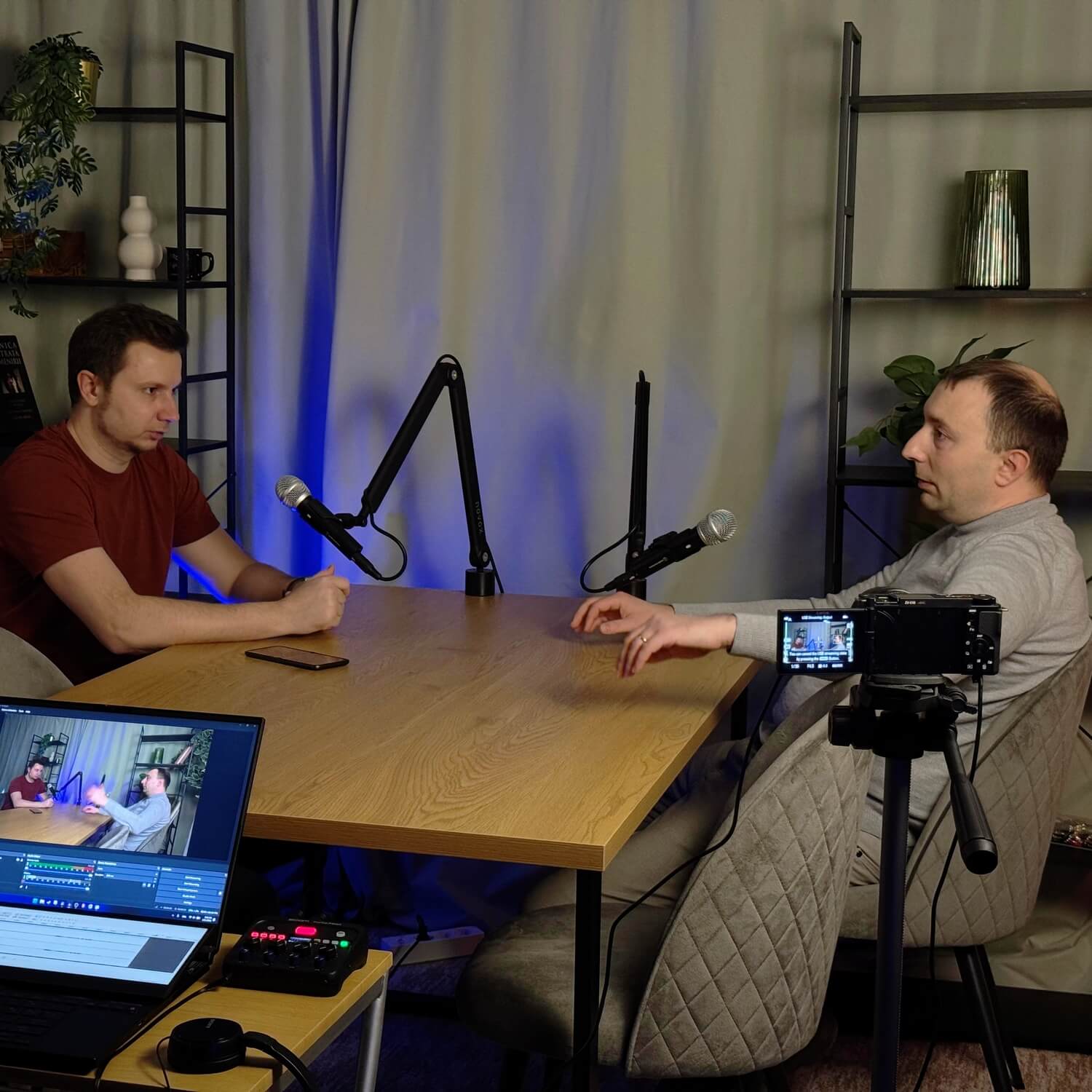 2 persoane la o masa de podcast