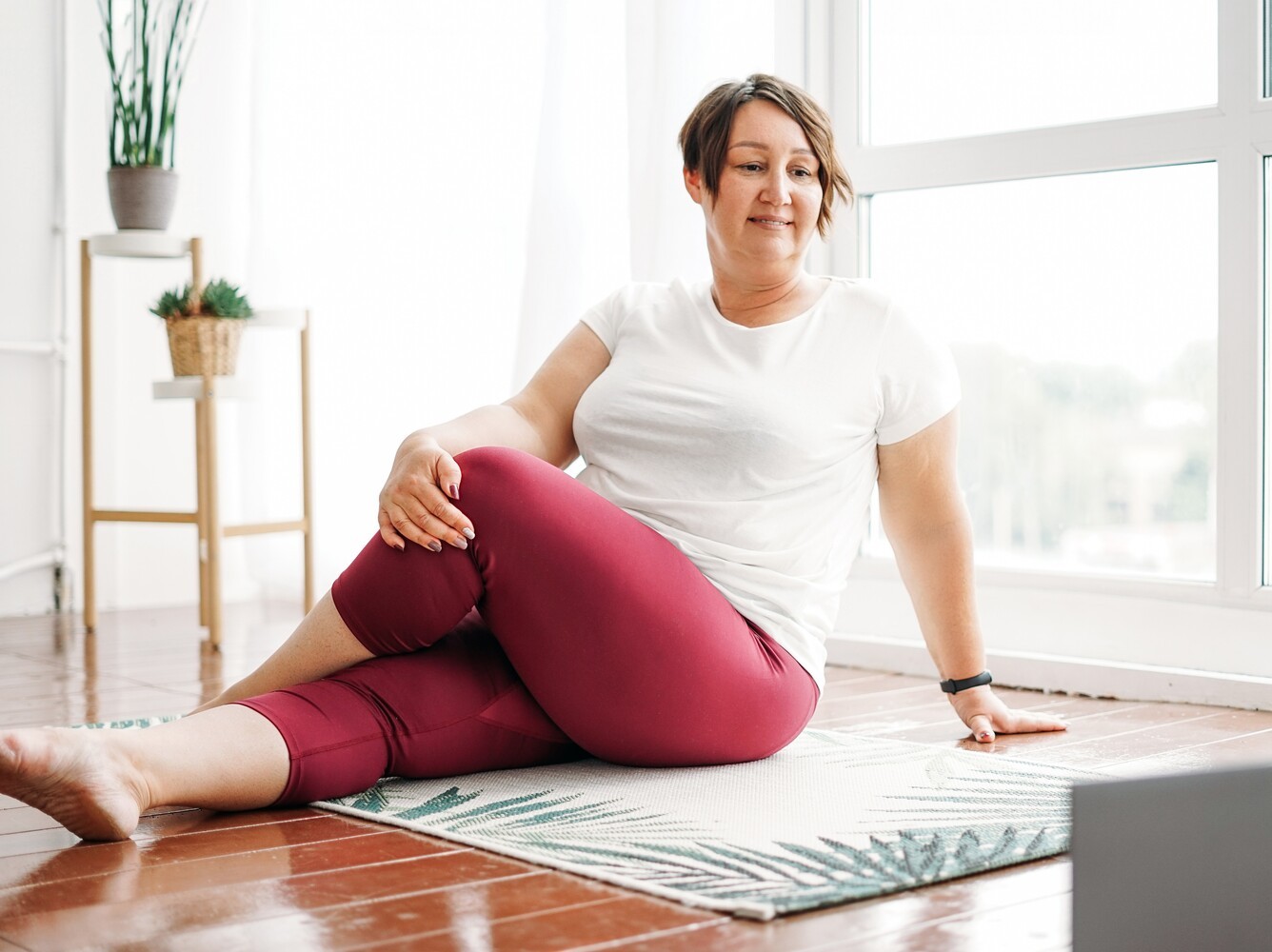 overweight woman following a yoga for beginners weight loss routine on her laptop to begin her fitness journey