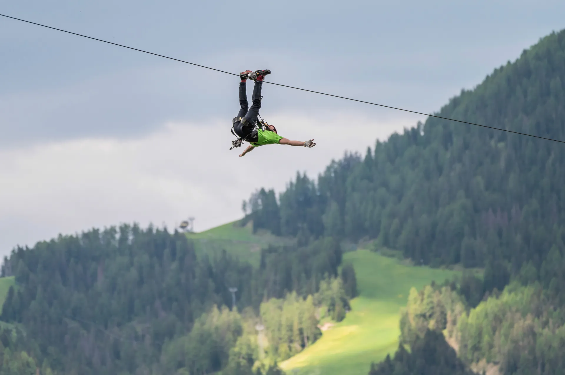 Volo capovolto sulla zipline con panorama delle Dolomiti verdi