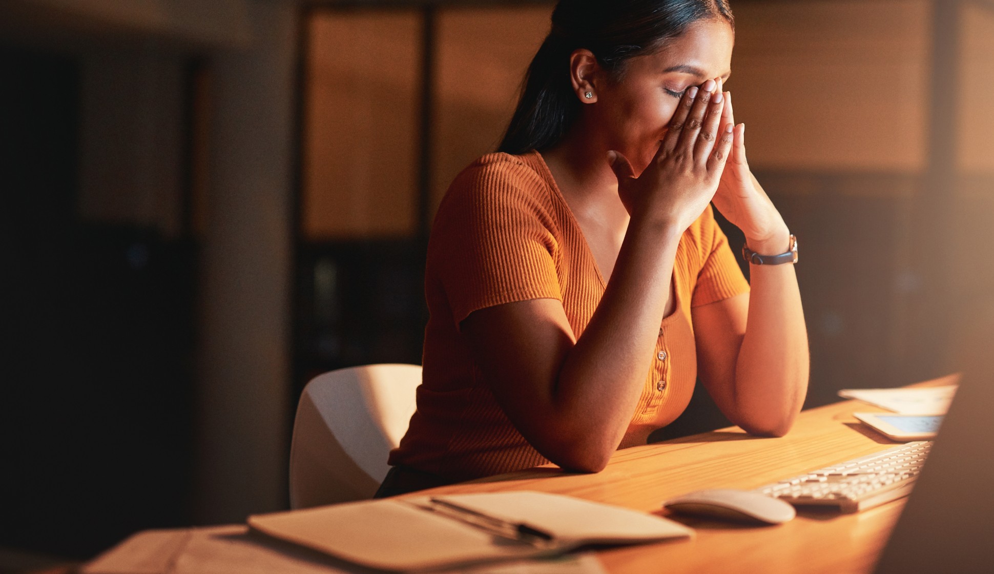 a young female provider sitting at night in front of her computer with eyes closed