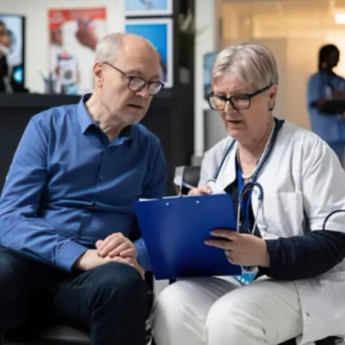 Medical practitioner reviewing clipboard information with a patient in a healthcare setting serving Coburg and Melbourne.