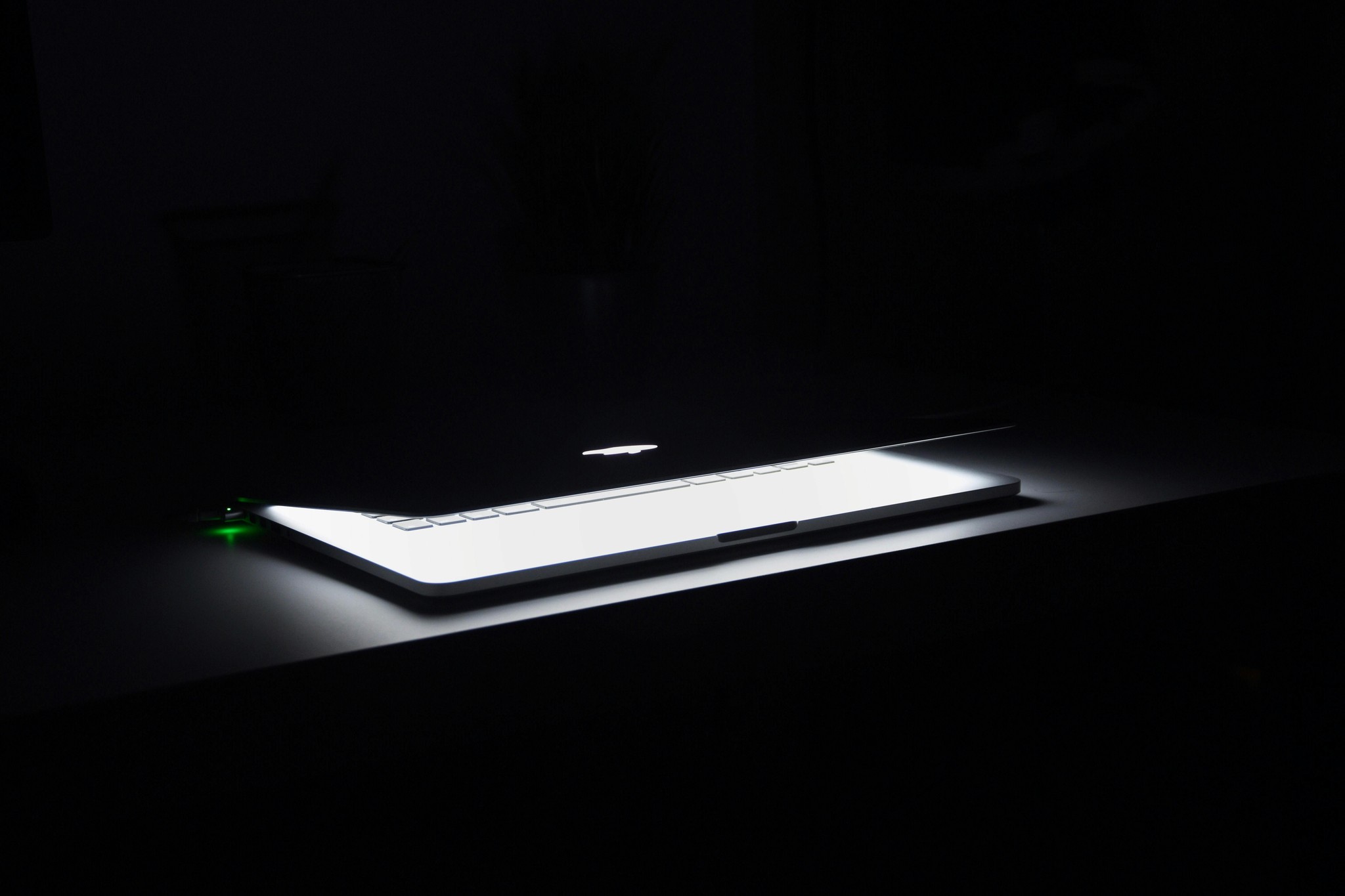 Partially closed laptop in a dark room, illuminated from within, showcasing a sleek and modern design.