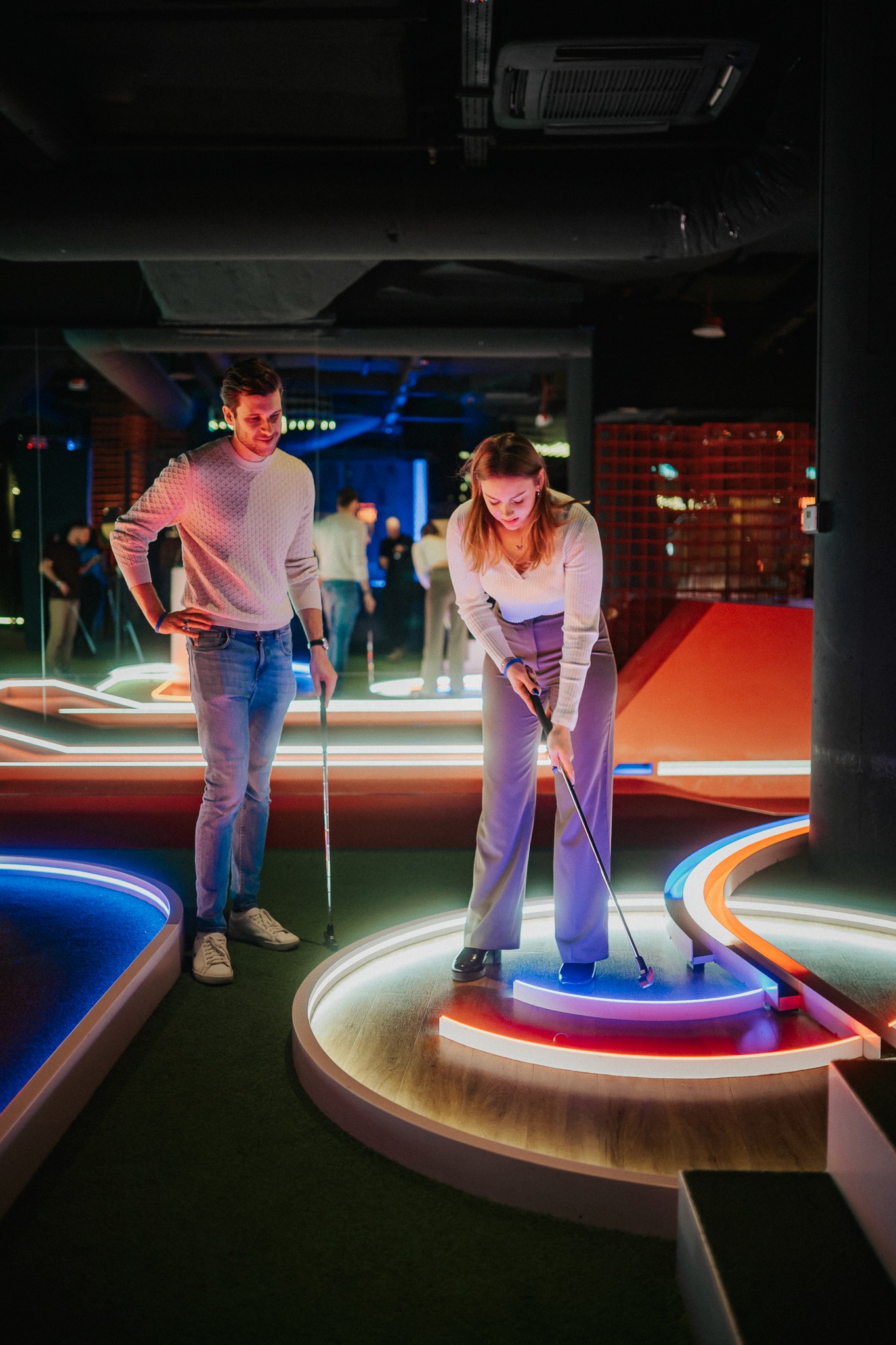 Grupa ludzi grających w mini golfa, korzystając z oferty activity baru, która obejmuje możliwość wydłużenia wykupionego slotu czasowego poprzez funkcję upsell