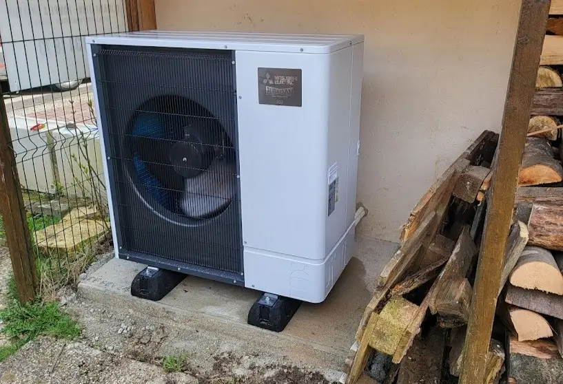 Pompe à chaleur air-eau installée à côté de rondins de bois dans une maison près de Thionville