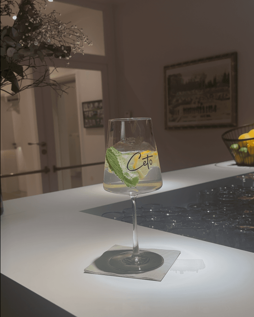 a glass of cocktail with a slime orange fruit