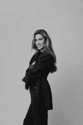 woman in red and blue jacket sitting on gray metal fence during daytime